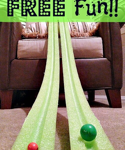 Two green pool noodles are positioned as racing tracks, each with a ball at the start. The phrase "FREE Fun!!" is displayed at the top in large text. Perfect for indoor activities for kids, the setup is placed in front of a cushioned chair with striped pillows.