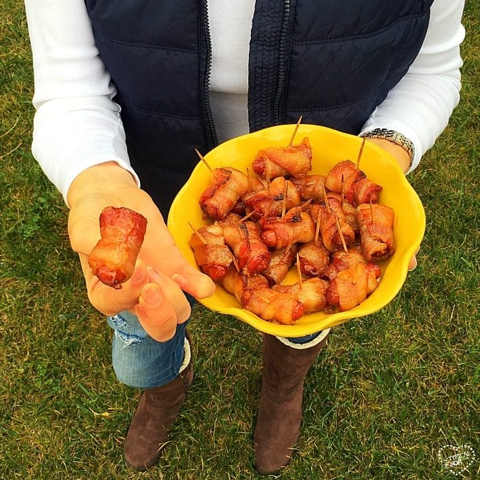 A person holds a yellow bowl filled with tantalizing bacon-wrapped hot dogs with brown sugar, offering one of these irresistible snacks to tempt your taste buds.