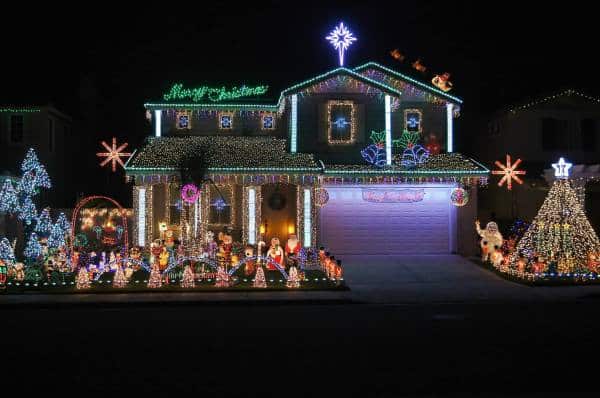 A house in Temecula is elaborately decorated with Christmas lights and decorations. The roof and exterior are outlined with multicolored lights, a large “Merry Christmas” sign, and various festive displays including a Christmas tree, Santa, and reindeer; it's truly a must-see on any holiday map.