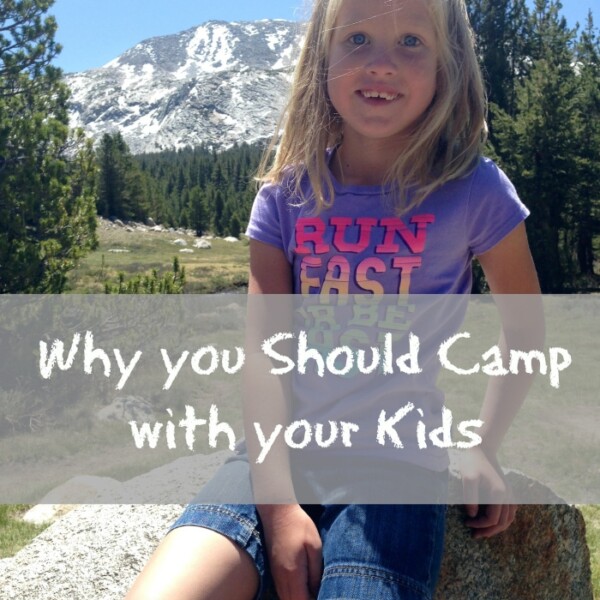 A young girl with blonde hair wearing a purple t-shirt and denim shorts sits on a rock in a mountainous area. Text over the image reads, "Why you should camp with your kids." The background includes trees and a snow-capped mountain, perfect for the best family vacations.