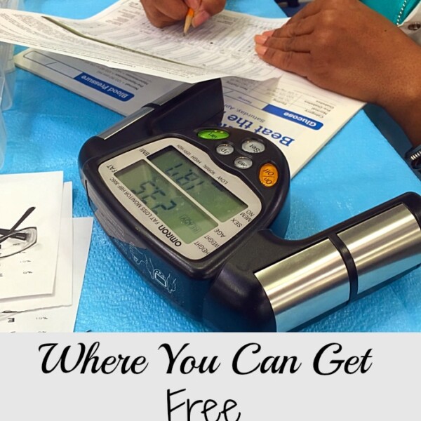 A person fills out forms at a health screening table, with a blood pressure monitor in sight. The text reads: Discover Where Free Health Screenings Are Available.