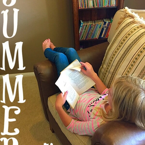 A child lounges on a chair, deeply engrossed in a book, with a bookshelf in the background. The scene perfectly captures the essence of summer reading programs.