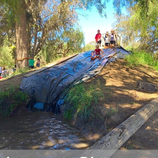 Children sit atop a slide at the Huntington Beach Adventure Playground, ready to dive into a day of fun and excitement.