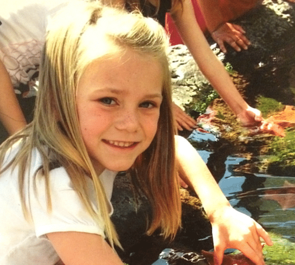 A young girl beams with joy as she touches a starfish in the tide pool exhibit, a perfect day made even better with free Sea World tickets for teachers.