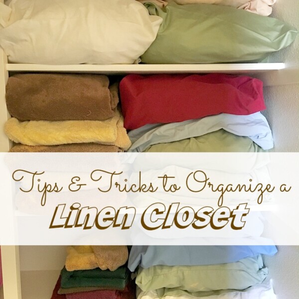 Neatly folded linens and towels stacked on white shelves, highlighting expert linen closet organization with a sign saying Tips & Tricks to Organize a Linen Closet.