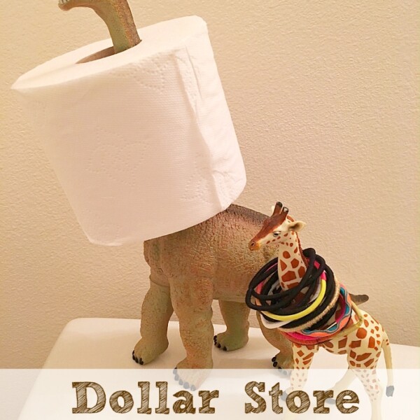 Plastic dinosaur and giraffe toys on a bathroom counter add whimsy to how you organize your bathroom, with the dinosaur cleverly holding a toilet paper roll and the giraffe stylishly wrapped in hair ties. Text reads Dollar Store Bathroom Hacks.