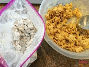 Two bowls of cereal mix, one with powdered sugar and the other plain, sit on a countertop, evoking the comforting flavors reminiscent of a Peanut Butter Muddy Buddies recipe.