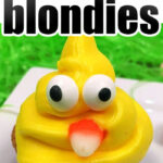 Cupcake with yellow icing shaped like an Easter chick, featuring candy eyes and a candy beak. Text above reads Easter blondies.