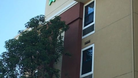 The charming hotel exterior, adorned with a leafy tree, proudly displays the Extended Stay America logo, inviting guests to enjoy a comfortable and convenient stay.