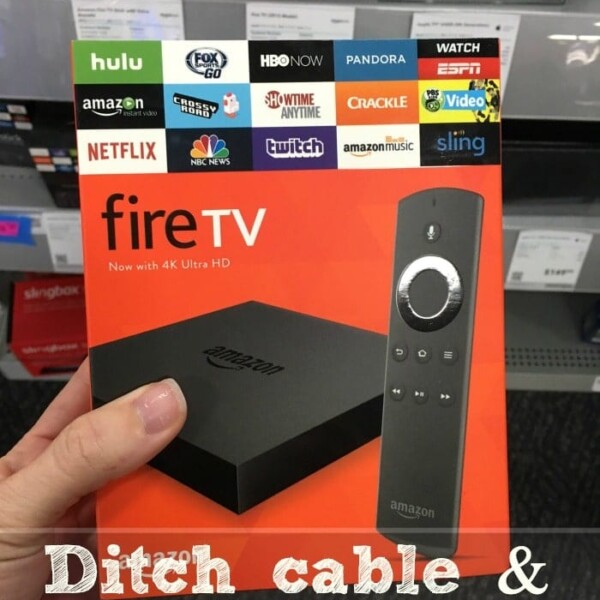 A hand holds a Fire TV box adorned with streaming service logos, inviting you to explore alternatives to cable and save $150 a month.