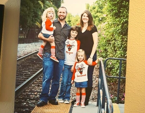 A family of five poses on a railroad track, with three children wearing matching holiday shirts, capturing the essence of togetherness. Stop making excuses and get in your family photos to create cherished memories like this one.