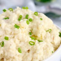 A bowl of slow cooker mashed potatoes topped with chopped green onions.