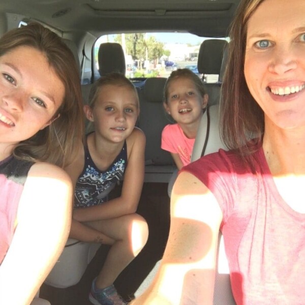 A woman and three girls smile while sitting in a 2017 Chrysler Pacifica, enjoying the spacious comfort of the car.