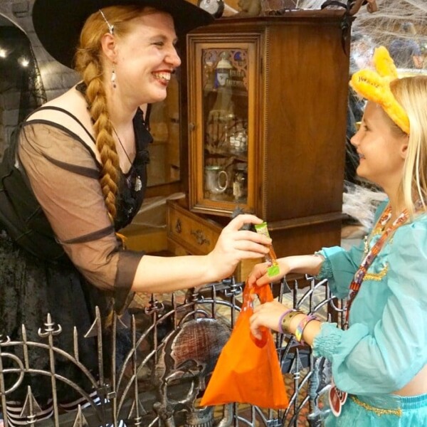 A woman in a witch costume gives candy to a child dressed as a fairy during Great Wolf Lodge's Howl-O-Ween celebration.