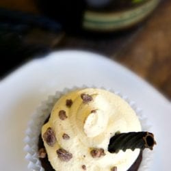 Baileys and cream cupcakes adorned with silky cream frosting, scattered chocolate bits, and an elegant chocolate curl.