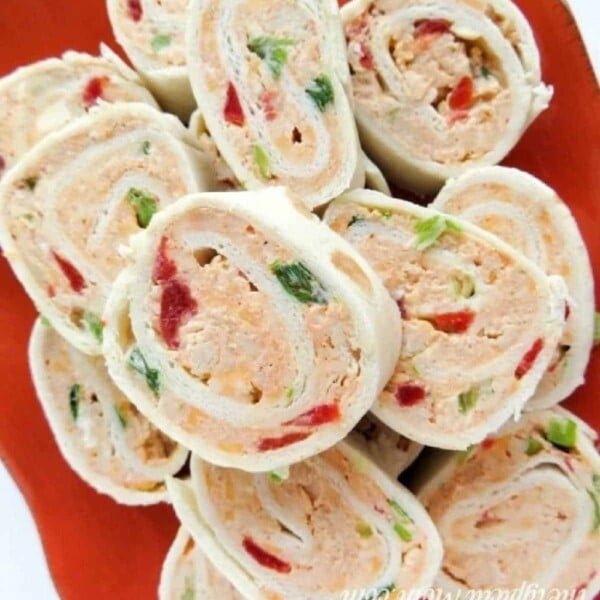 Cream cheese pinwheels with peppers elegantly arranged on an orange plate.