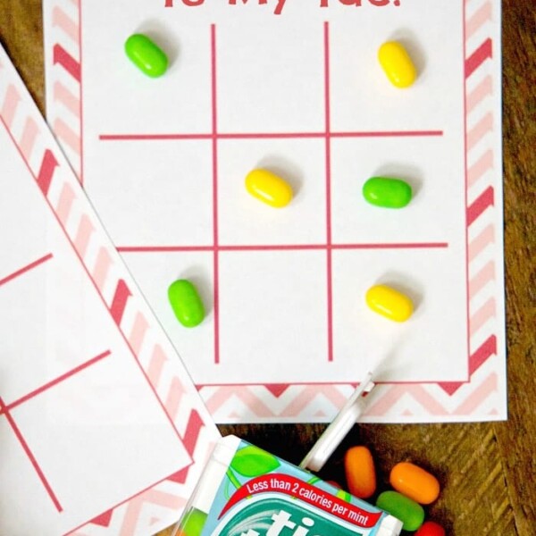 Tic Tac game board with candies, a pack of Tic Tac, and a pen on a wooden table. Text: You’re The Tic To My Tac. Perfect for kids Valentine cards, this sweet setup is an adorable way to say you care.