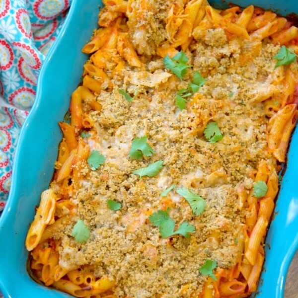 Baked penne pasta in a blue dish topped with breadcrumbs and garnish, with a colorful cloth beside it, becomes an effortless delight in this no-boil chicken parmesan casserole.