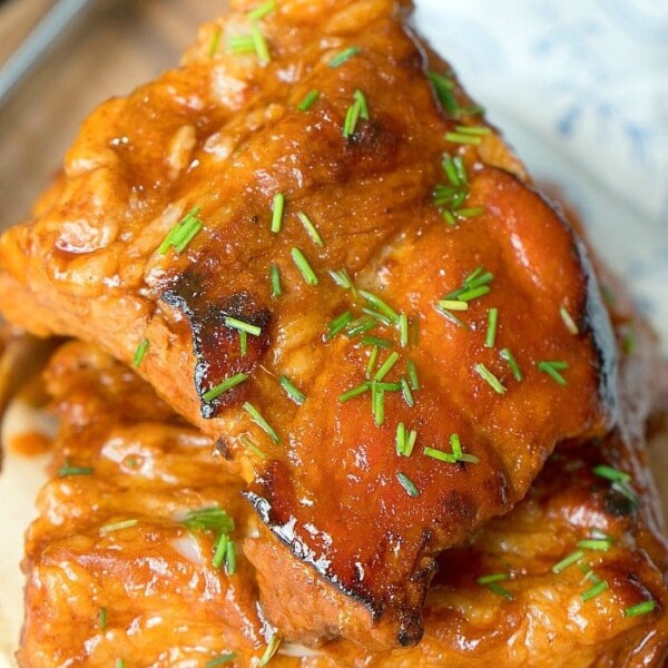 Two pieces of Crock-Pot Express ribs. Glazed and juicy, with a fork and cloth napkin partially visible in the background.