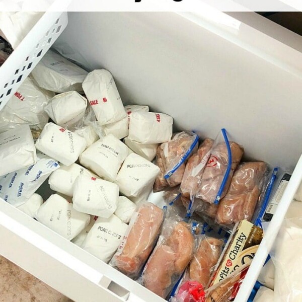 Open freezer filled with meats wrapped in white paper and plastic bags, highlighting the perks of choosing to buy bulk meat online. Casual shoes peeking from the bottom add a personal touch to this cost-effective approach.