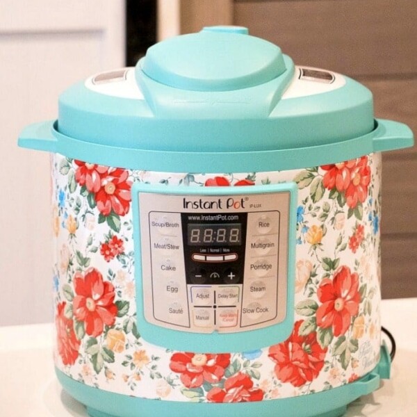 A brightly colored multi-cooker with a floral pattern graces the white kitchen counter, perfect for whipping up instant pot Thanksgiving recipes. It features a digital display and various labeled buttons for diverse cooking options.