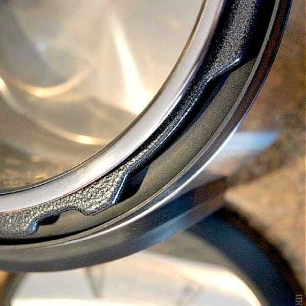 Close-up of a pressure cooker lid with gasket, resting on a blurred kitchen surface—a crucial step when learning how to clean your Instant Pot efficiently.