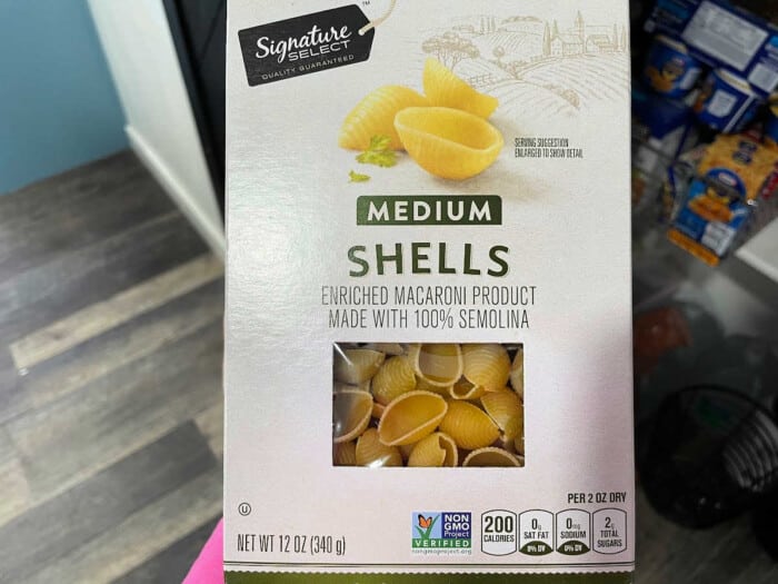 Box of Signature Select medium shells pasta, an enriched macaroni product made with 100% semolina, perfect for dishes like instant pot sloppy joe casserole. Includes nutrition facts: 200 calories per serving, non-GMO verified. Box design features pasta image and Tuscany-inspired illustration. Net weight 12 oz.