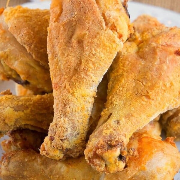 A plate of crispy, golden-brown air fryer fried chicken drumsticks piled together.