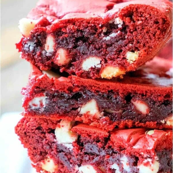 Close-up of three red velvet brownies made from cake mix, neatly stacked to reveal a dense, rich texture studded with visible white chocolate chips.