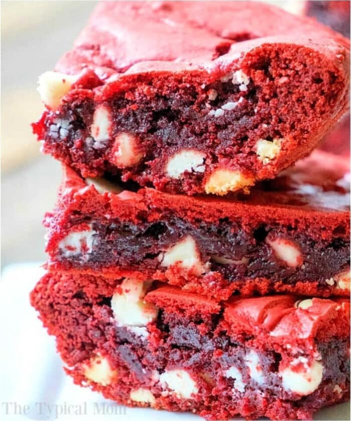 Close-up of three red velvet brownies made from cake mix, neatly stacked to reveal a dense, rich texture studded with visible white chocolate chips.