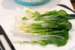 Fresh bok choy, washed and halved, displayed on a white cutting board—perfect for learning how to make bok choy dishes at home.