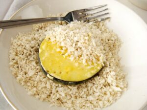 A slice of eggplant coated with breadcrumbs sits invitingly on a plate, reminiscent of air fryer eggplant chips, with a fork poised elegantly beside it.