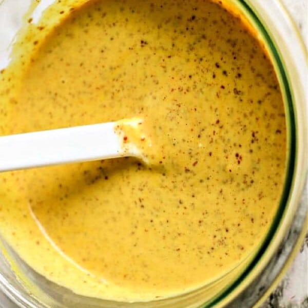 A bowl of homemade dijon mustard pretzel dip with a white spoon.