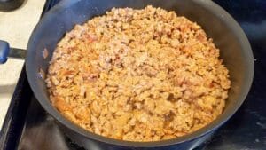 Cooked seasoned ground meat in a black skillet on a stovetop, perfect for adding rich flavor to your favorite crockpot tortellini soup recipe.