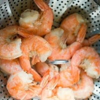 Steamed shrimp cooked to perfection in an Instant Pot, nestled in a metal basket with a perforated design.