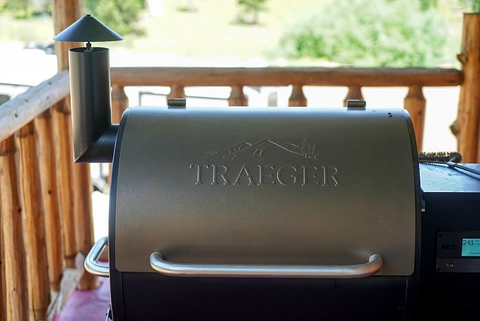 A Traeger grill on a wooden deck, with a visible chimney and engraved logo on the lid, awaits the best meats to smoke for your next flavorful feast.