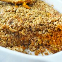 Baked sweet pumpkin crisp casserole with oat crumble topping in a white dish, reminiscent of a pumpkin crisp without cake mix.