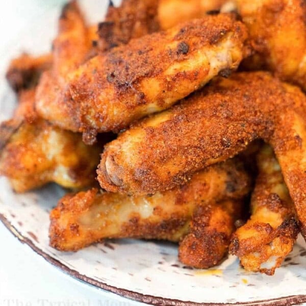 A plate filled with crispy, golden brown air fryer wings stacked on top of each other. The wings are seasoned with visible spices and appear to be freshly cooked. The edges of the plate are slightly visible, making this recipe a feast for both the eyes and taste buds.