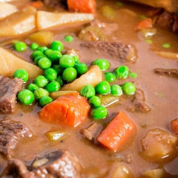 Hearty beef stew with tender stew meat, carrots, peas, and potatoes in a rich broth, cooked to perfection in an Instant Pot and served warm in a pot.