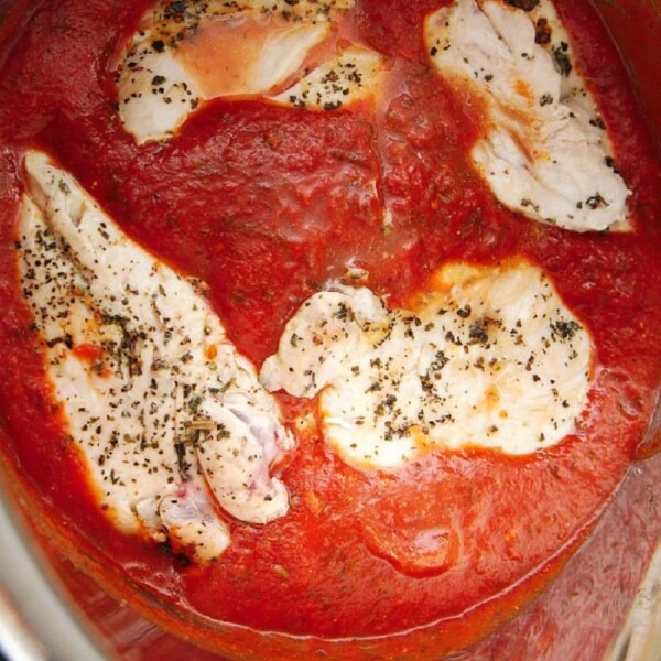 Chicken breast slices in a tomato sauce, garnished with herbs, create a delightful instant pot chicken parmesan.