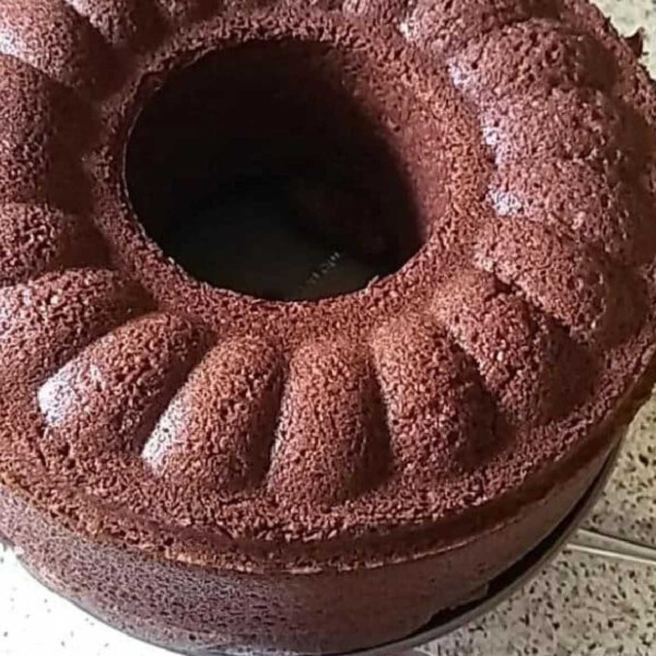 A circular chocolate Bundt cake on a speckled countertop, with a ridged pattern and center hole, echoing the decadence of Ninja Foodi brownies.