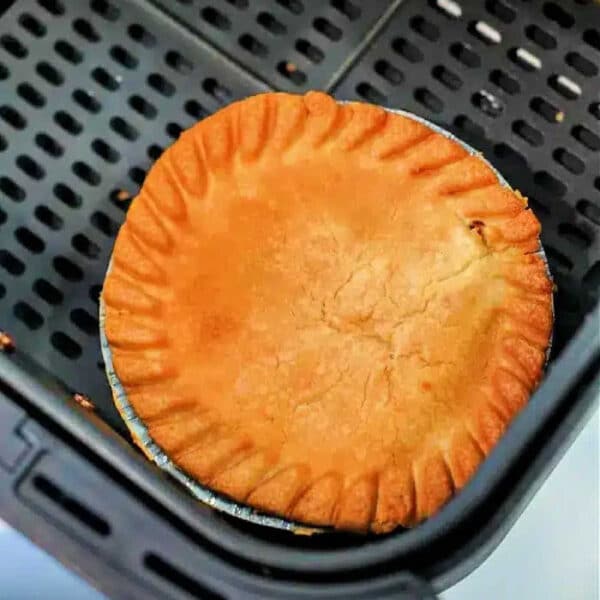 A golden-brown frozen pot pie in air fryer sits perfectly crisp in the basket, ready to be served.