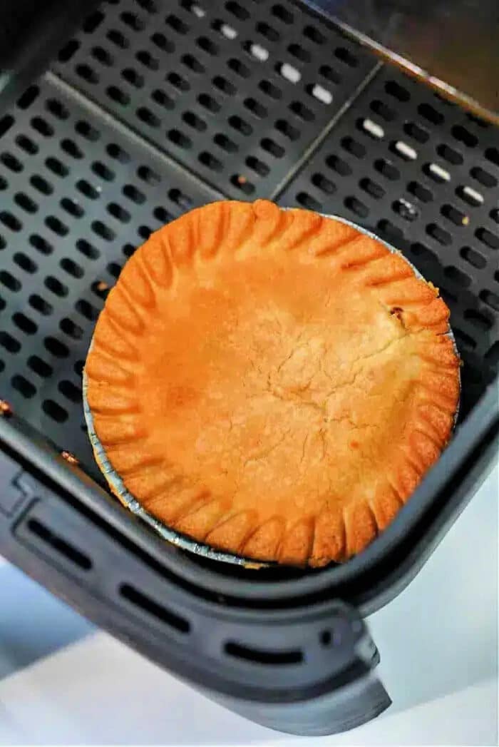 A golden-brown frozen pot pie in air fryer sits perfectly crisp in the basket, ready to be served.