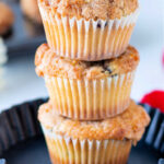 Three stacked frozen blueberry muffins rest elegantly in a black baking dish on a light background.