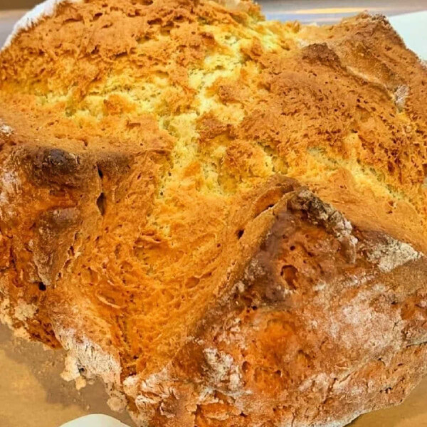 Golden-brown, freshly baked No Yeast Irish Soda Bread rests on a baking tray lined with parchment paper.