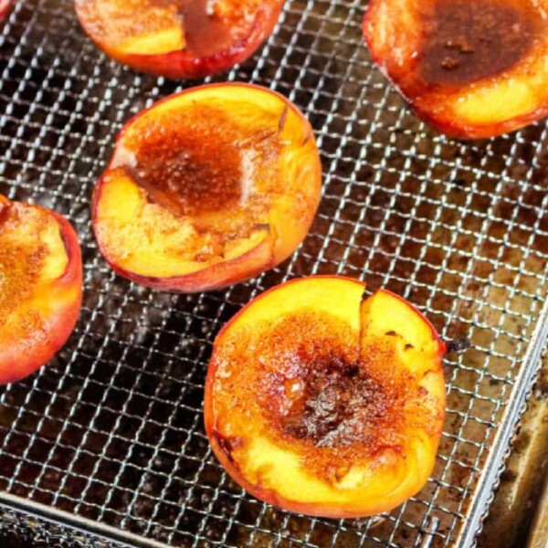 Halved peaches topped with brown sugar on a wire rack, ready to transform into air fryer peaches, set on a baking tray.