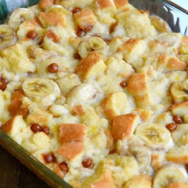 Close-up of an easy banana bread pudding with banana slices and bread cubes in a glass baking dish.