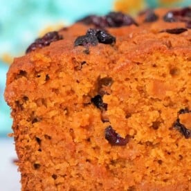 Close-up of a slice of easy pumpkin bread, against a colorful background.