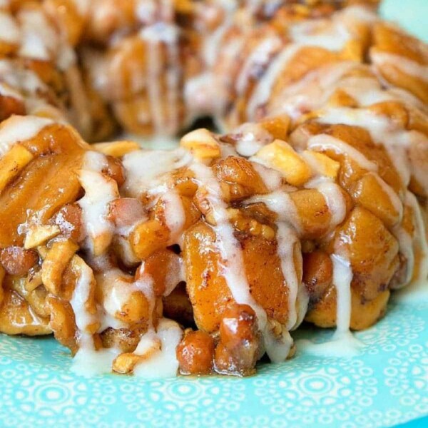 A close-up of a cinnamon roll monkey bread, effortlessly made in an Instant Pot, drizzled with icing and served on a decorative blue plate.