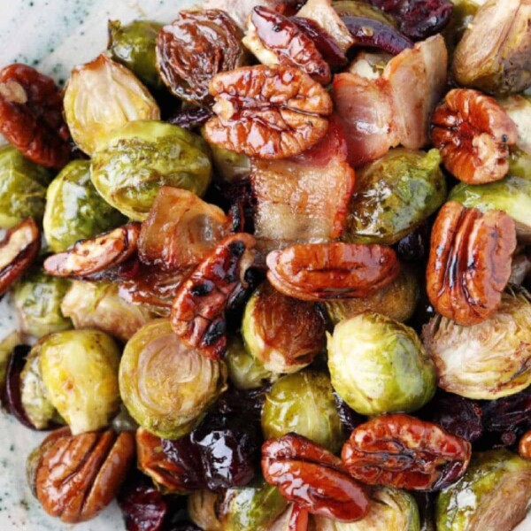 Air-fried roasted Brussels sprouts with pecans and cranberries elegantly presented on a white plate.